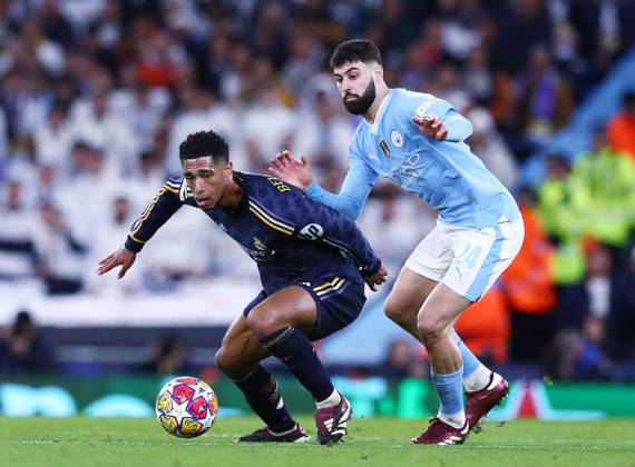 Jude Bellingham u dresu Real Madrida vodi loptu pred Joškom Gvardiolom u dresu Manchester Cityja